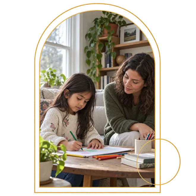 A therapist sitting beside a young girl as she draws with colored pencils